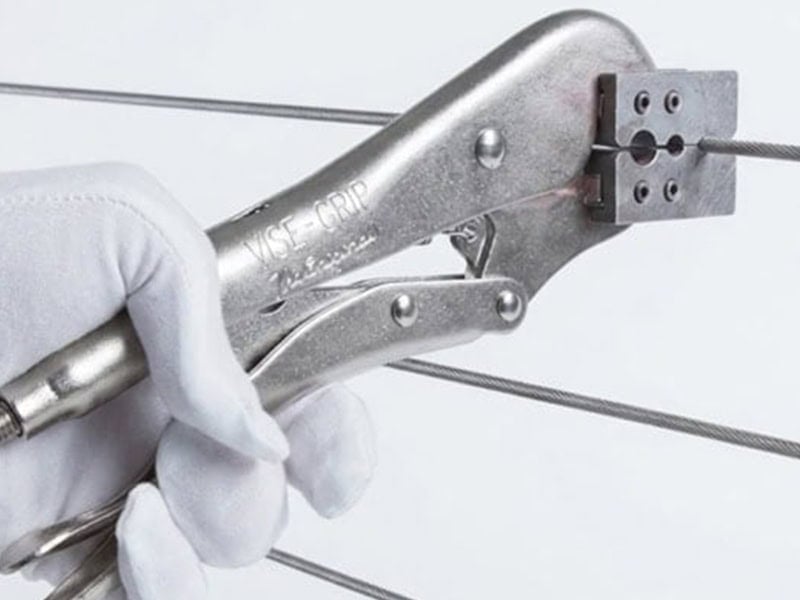 Locking pliers crimping a stainless steel cable fitting during cable railing installation