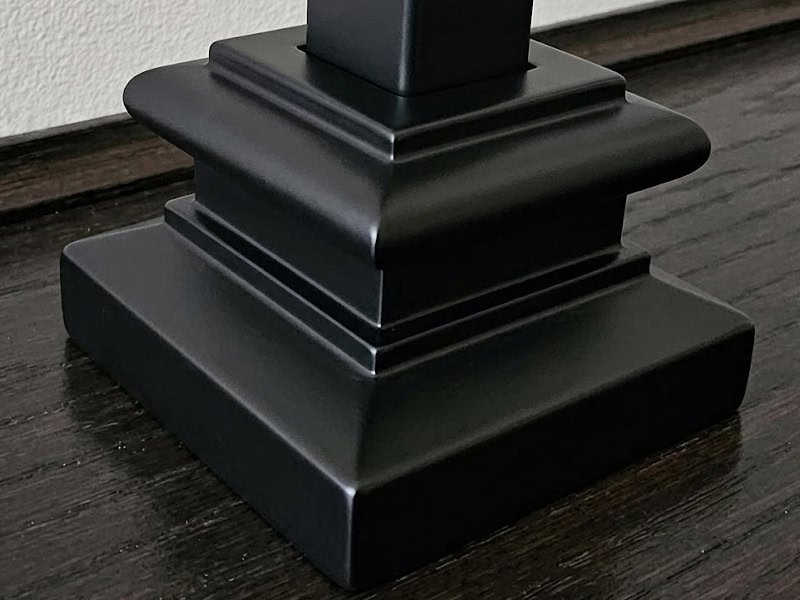 Black iron newel post base installed on a dark wood floor