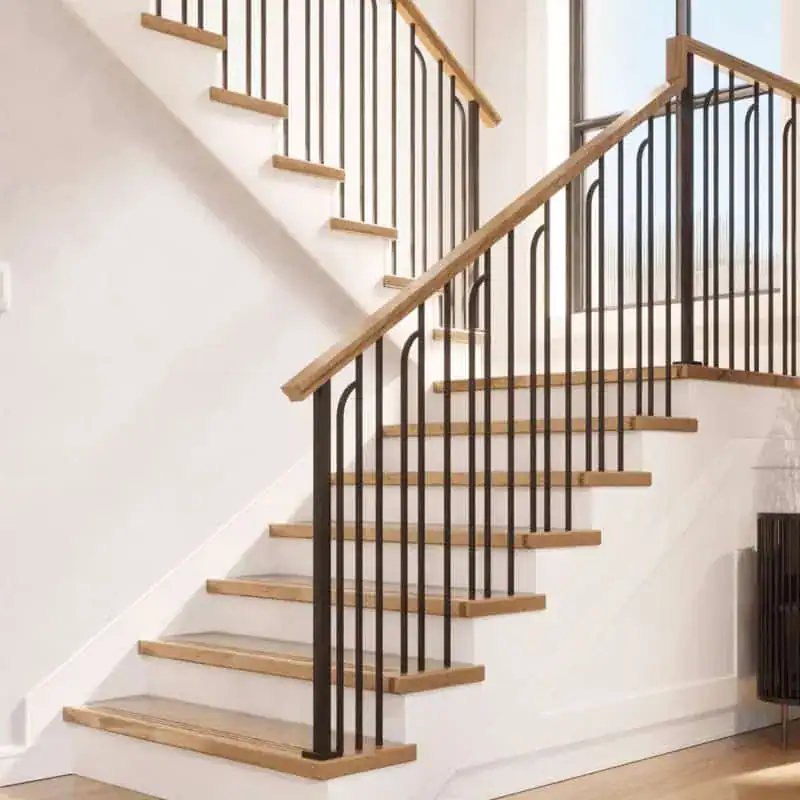Linéa arched iron balusters with square iron newel posts, an oak handrail and oak treads on an L-shaped staircase