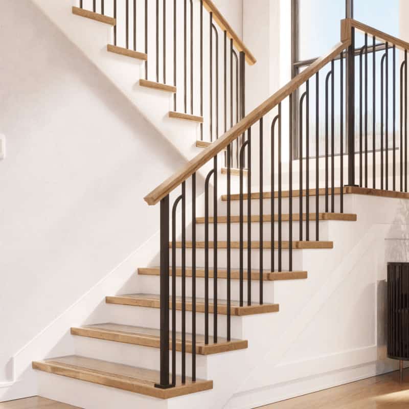 Linéa arched iron balusters with square iron newel posts, an oak handrail and oak treads on an L-shaped staircase