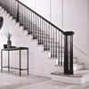 Röhe pin top newel post on a staircase with black balusters and handrail