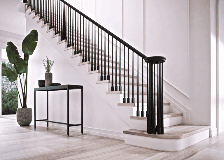 Röhe pin top newel post on a staircase with black balusters and handrail