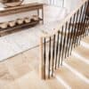 Röhe pin top newel post at the bottom of a staircase with black iron balusters