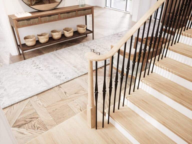 Röhe pin top newel post at the bottom of a staircase with black iron balusters