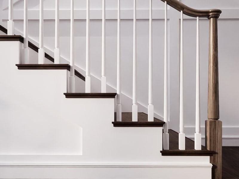 Röhe tapered wood newel post and handrail with white tapered balusters on dark stained stair treads