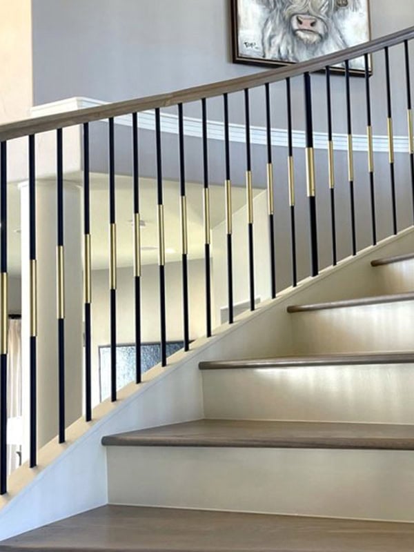SoHo round black iron balusters with brass sleeves on a curved staircase