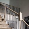 Staircase with a Röhe stabilizer newel post and iron balusters